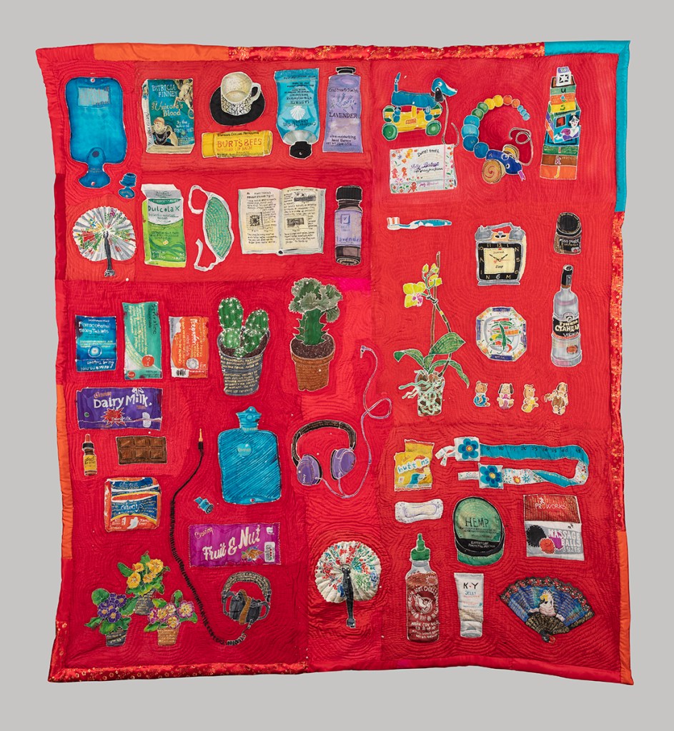 A large quilt in red silk. Featuring a large collection of objects representing the menopause. Created using batik and machine stitch.