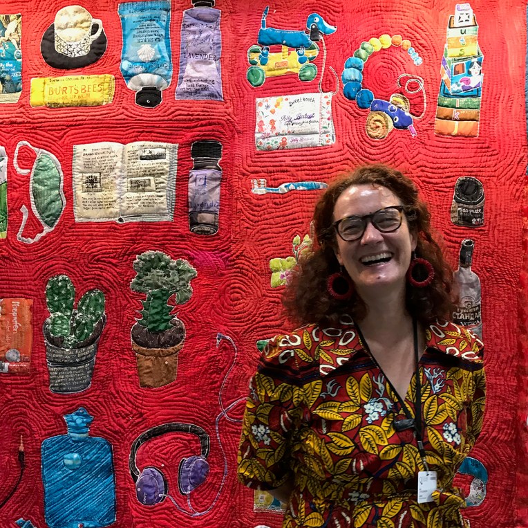 Artist Lois Blackburn in front of her quilt, Blood, Sweat and Tears, the Menopause Quilt