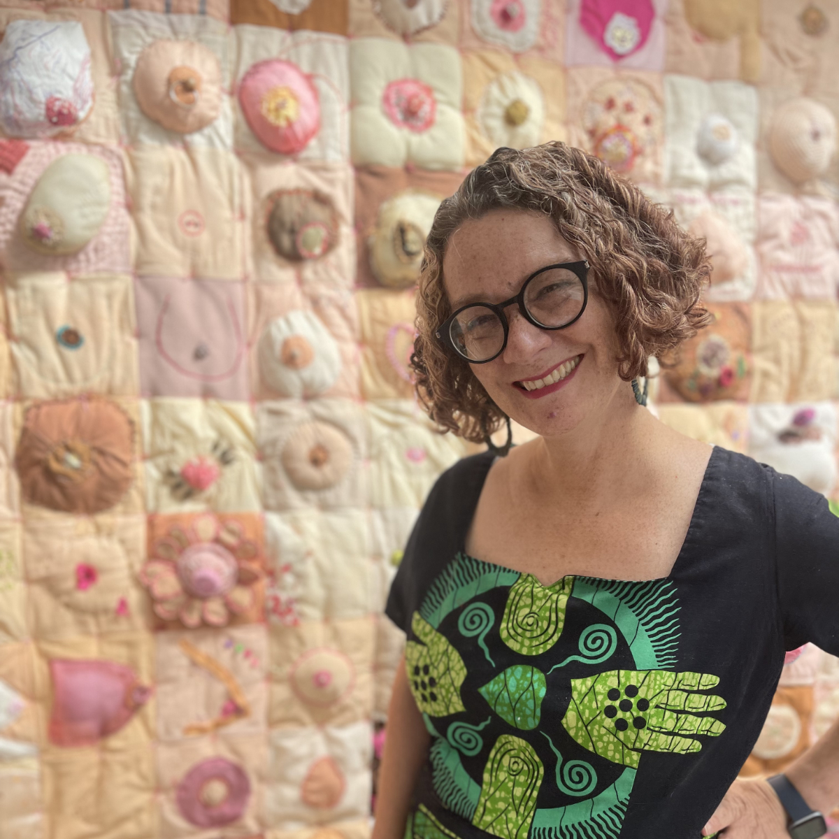 Artist Lois Blackburn standing in front of her work, Comfort the Breast quilt