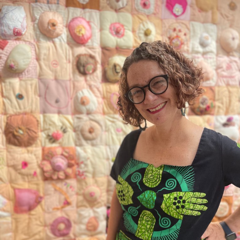 Artist Lois Blackburn standing in front of her work, Comfort the Breast quilt