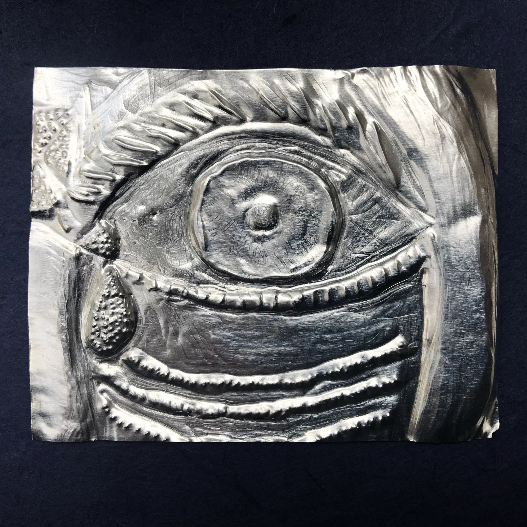 Evil eye amulet, made from embossed metal, staring eye, with tear drop. Symbolic of recovery