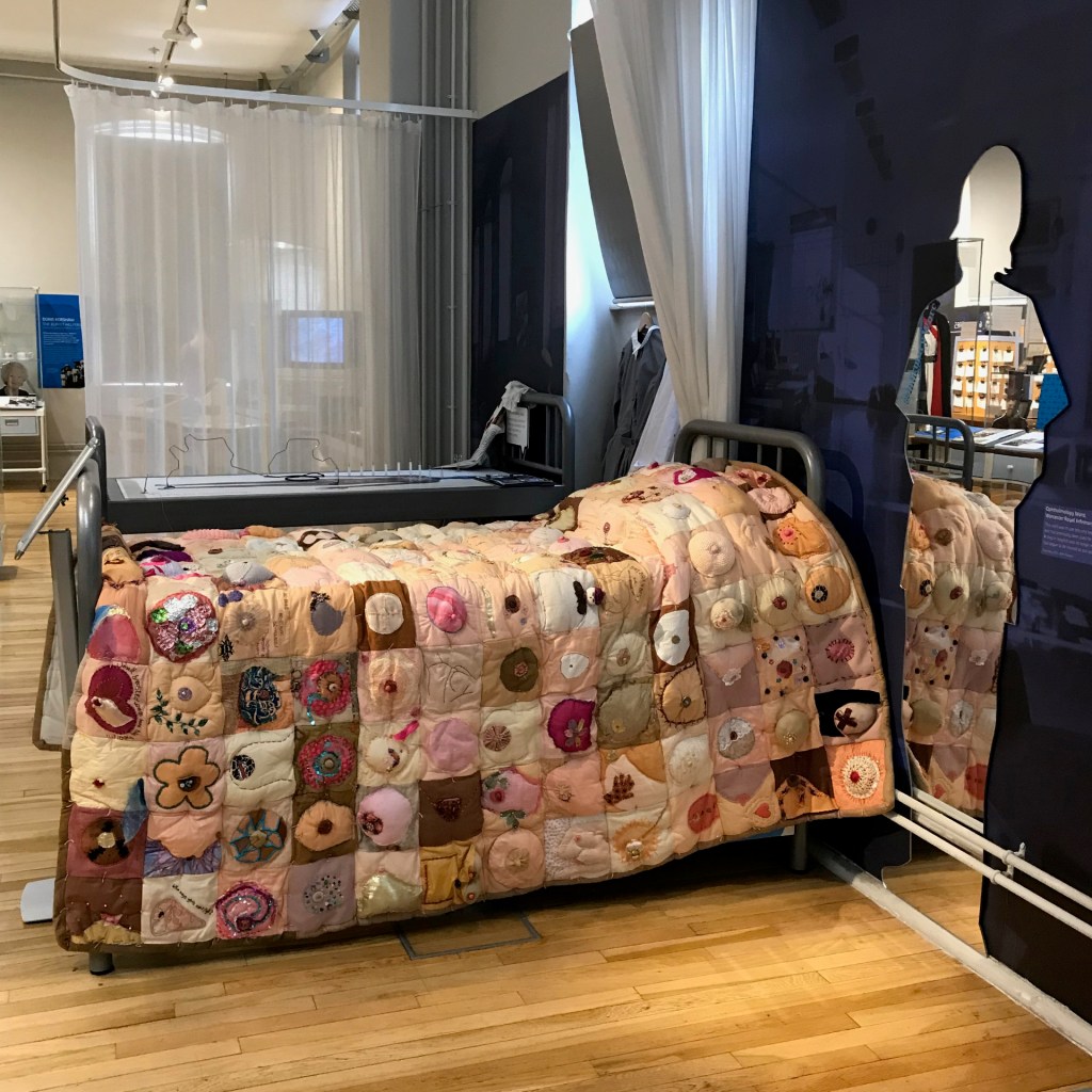 Comfort the Breast quilt on exhibition at The Infirmary Museum, Worcester. Displayed on a hospital bed.