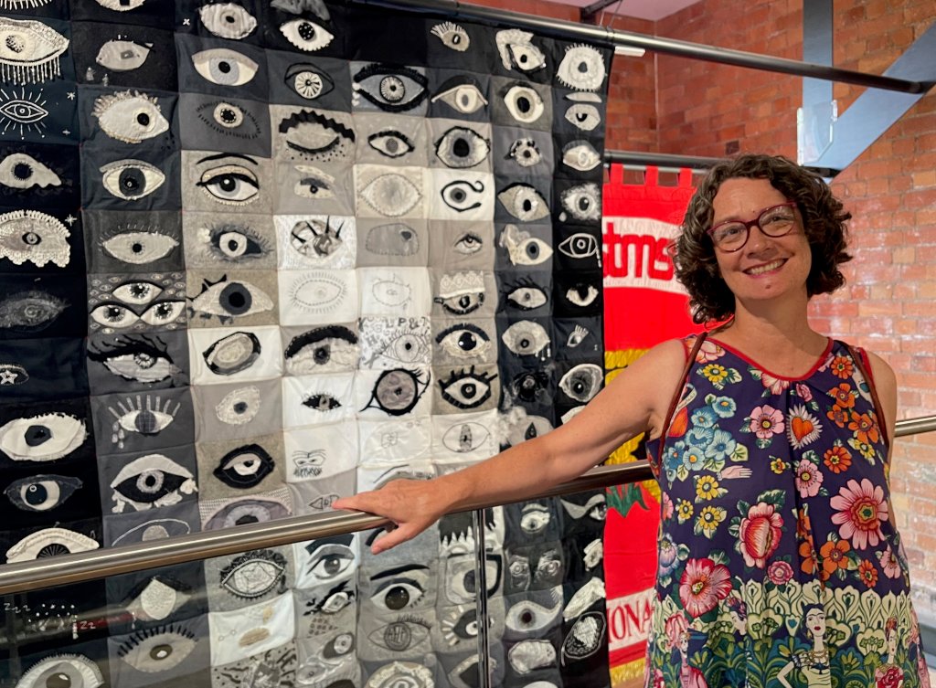 Artist Lois Blackburn, beside the quilt I SEE you, on exhibition at Museum of Making