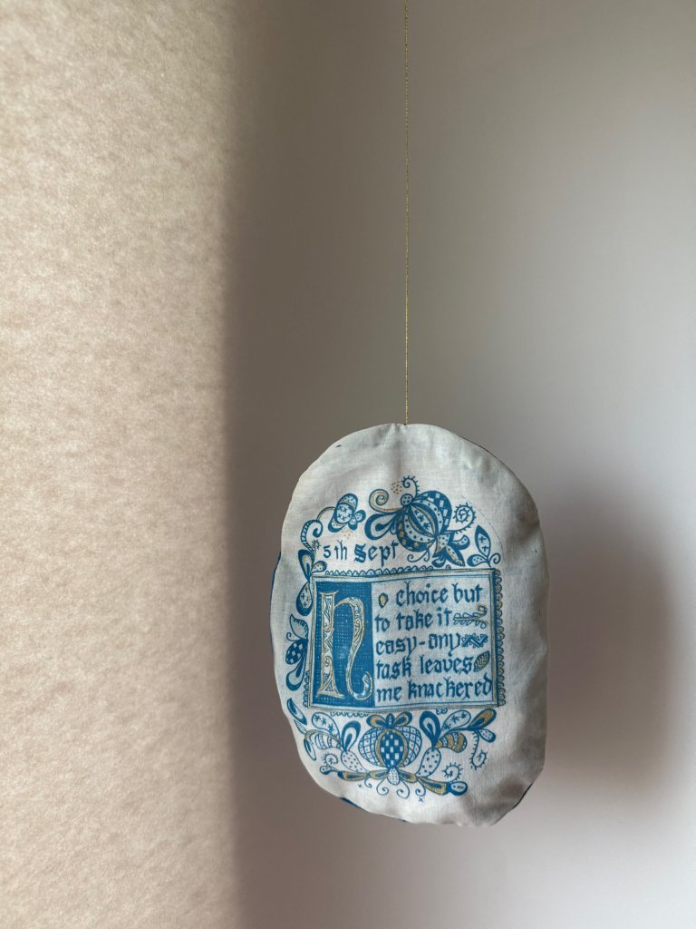 Stoma bag cover, cyanotype on fabric with hand calligraphy and celtic knot illustration, part of Under Repair series by Lois Blackburn.