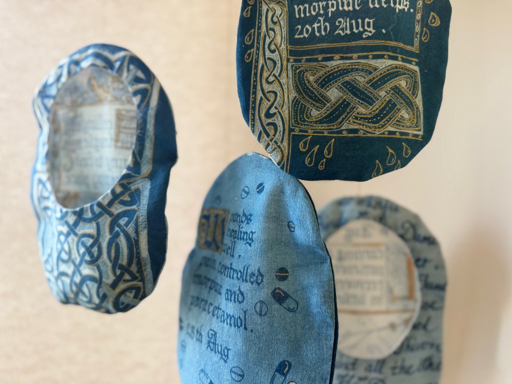 Stoma bag cover, cyanotype on fabric with hand calligraphy and celtic knot illustration, part of Under Repair series by Lois Blackburn.