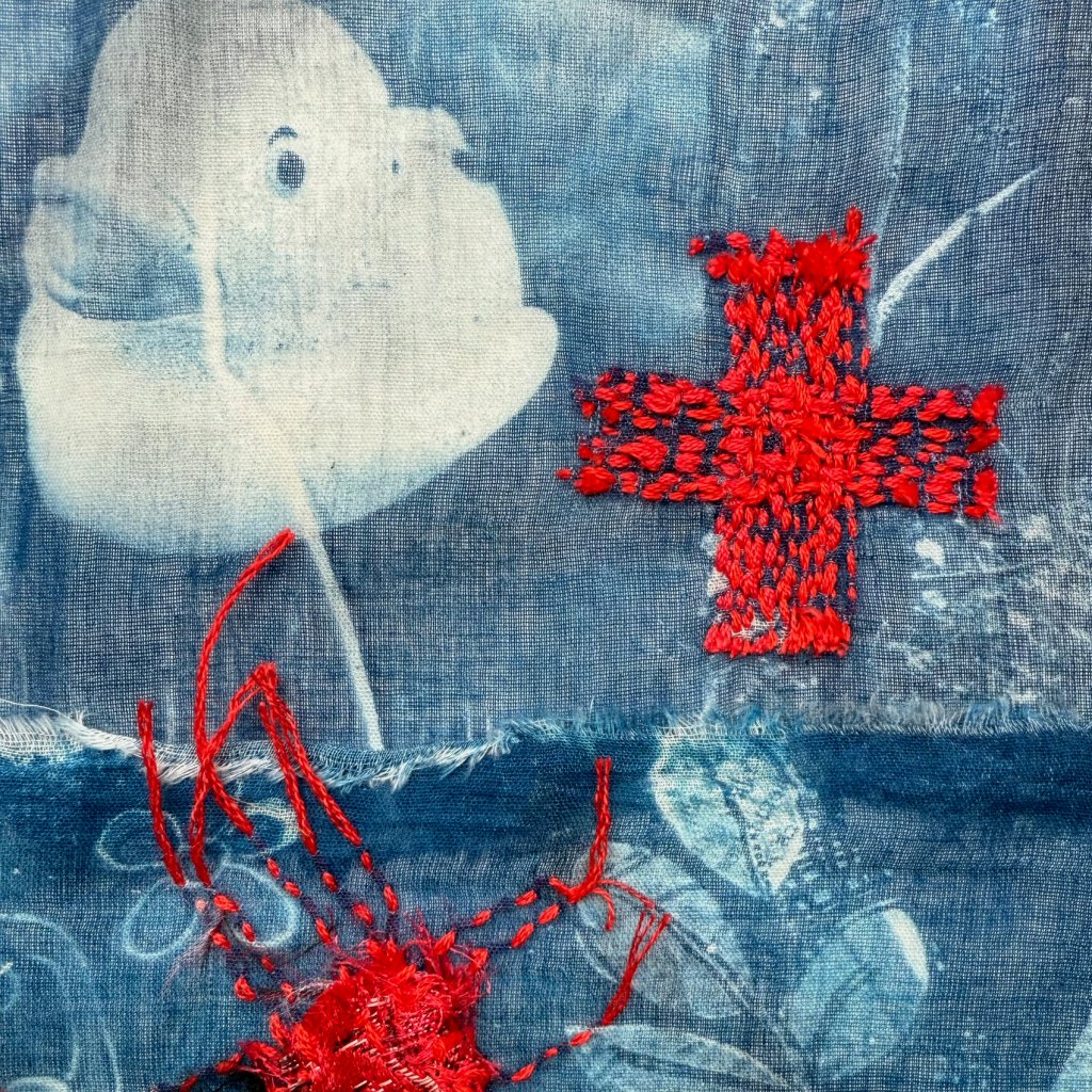 Embroidered cyanotype on fabric sample. Part of Lost then Found series by Lois Blackburn. Picturing glasses, Rubber duck, keys and embroidered red crosses